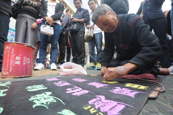 Cui Xianren, who was severely injured in an explosion, earns money by writing characters with chalk on the street in Qingdao, Shandong province, on Oct 12. Handicapped street artist writes his way to fame