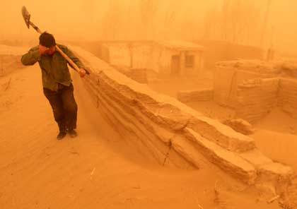 A Chinese farmer walks amid a heavy sand storm in Minqin County, northwest of China's Gansu Province April 10, 2006. A strong sandstorm hit northwest China on Monday, killing one person in Xinjiang Uygur Autonomous Region and compelling dozens of trains to halt for safety reasons. [Newsphoto]