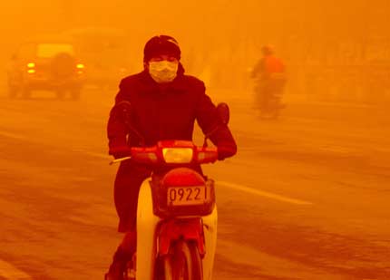 A resident rides a motorcycle through a heavy sand storm on a street in Turpan, China's Xinjiang Uygur Autonomous Region April 10, 2006. A strong sandstorm hit northwest China on Monday, killing one person in Xinjiang Uygur Autonomous Region and compelling dozens of trains to halt for safety reasons. [Newsphoto]
