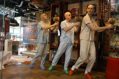 Australian group the Urban Dream Capsule perform in a glass box in a shopping mall in Shanghai, June 20, 2006. The four Australian men will live in the glass box for 12 days, with the public able to watch them sleeping, eating and bathing, a news report said Thursday. [Newsphoto]