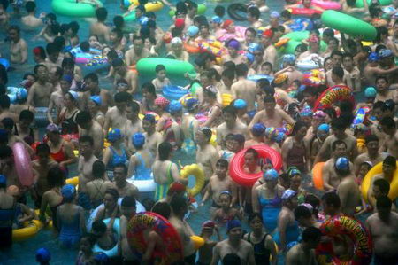 Thronging swimmers stand in Taiyanggong Swimming Pool in Nanjing, capital of east China's Jiangsu Province Sunday, July 30, 2006, as the local temperature hit 36.2 degrees centigrade. With the abundant people going there to beat the heat, swimmers can only stand in the water rather than swim freely. [IC]