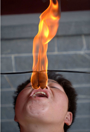 Liu Gang tries to extinguish a torch by putting it into his mouth during a stunt performance at a park in Hefei, east China's Anhui province October 2, 2006. China is celebrating a week-long National Day holiday, which started on Sunday, a time when millions of Chinese travel to major cities to enjoy cultural attractions or return home to visit relatives and friends. [Reuters]