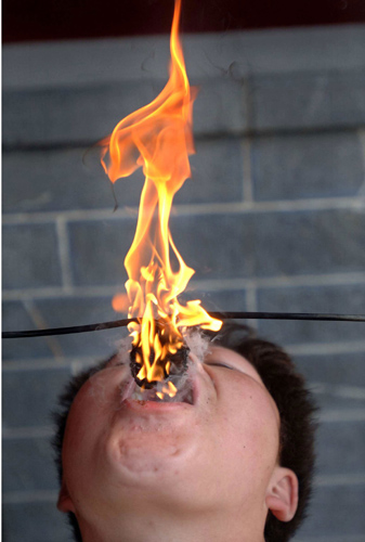 Liu Gang tries to extinguish a torch by putting it into his mouth during a stunt performance at a park in Hefei, east China's Anhui province October 2, 2006. China is celebrating a week-long National Day holiday, which started on Sunday, a time when millions of Chinese travel to major cities to enjoy cultural attractions or return home to visit relatives and friends. [Reuters]1