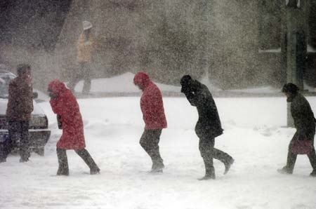 People walk through a street during heavy snowfall in Shenyang, Northeast China's Liaoning Province, March 4, 2007. Most vehicles in Shenyang are forbidden to hit the road on Monday except those for public use to ensure the smooth cleanup and transportation of snow, which hit the city on Saturday night and caused major traffic troubles. [Xinhua]