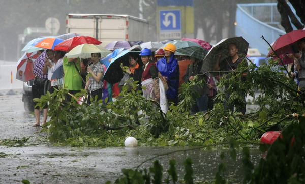 Residents in Haikou, capital of South China's Hainan province, get stuck on a street flooded by torrential rain caused by Typhoon Nesat on Thursday. High-risk areas evacuated before typhoon