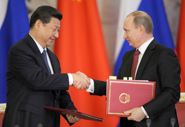 President Xi Jinping shakes hands with Russian President Vladimir Putin during a document signing ceremony in Moscow. Opportunities, not threats