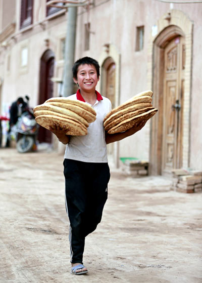 A young Uygur man on his way to deliver naan bread to customers in Kashgar ahead of Eid-al-Adha Festive cheer in Xinjiang