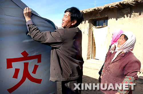2003年11月12日，甘肅山丹縣李橋鄉(xiāng)劉莊村黨支部書記王升（左）在該村七社村民王金秀（右）家檢查抗震救災(zāi)帳篷密封情況。2003年10月25日，甘肅山丹縣發(fā)生6.1級(jí)地震后，該縣廣大黨員干部一直奮戰(zhàn)在抗震救災(zāi)第一線。 新華社發(fā) 