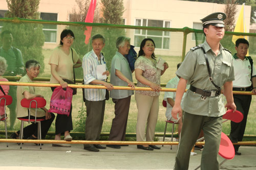 A security man carries a charir at the venue for a vote on demolishment and reconstruction of old buildings in Juixiaqiao Sub-district in Beijing, June 9, 2007. Local government and the real estate developer jointly organize the vote on Saturday to see if majority residents of over 5000 families accept the new compensation policy after failed attempts to reach an agreement through other ways. Both notary officials and supervisors are invited to monitor the vote that runs from 9 a.m. to 9 p.m. at six ballot booths. [Sun Yuqing/www.midnightarchive.com]