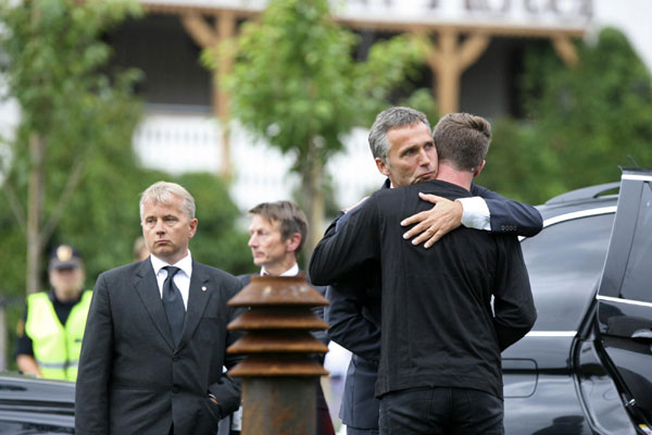 Norway's Prime Minister Jens Stoltenberg is flanked by Justice Minister Knut Storberget (L) and State Secretary Hans Kristian Amundsen (2nd L) as he hugs Labour Youth Wing leader Eskil Pedersen (R) in Sunvold July 23, 2011 Norway's PM comforts attack survivors