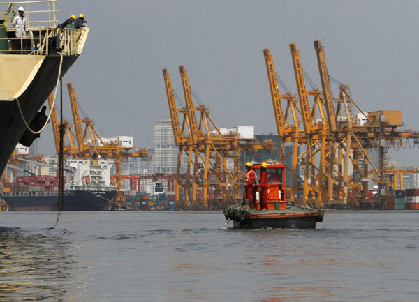 Workers work on a boat at Bangkok port as water seeps into the container storage area from the Chao Phraya river in Bangkok Oct 31, 2011. Thailand hopes industrial estates swamped in its worst floods in half a century can be up and running within three months, the prime minister said on Monday, as the centre of the capital finally appeared to have escaped a similar fate. Thailand hopes flooded industrial estates back up