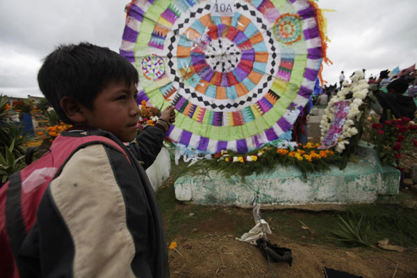A boy holds a kite set up on a grave in the cemetery of Santiago Sacatepequez, 40 km (24 miles) from Guatemala City Nov 1, 2011. Dating back 112 years, the tradition of flying kites in the cemeteries of Guatemala integrates the Catholic feast of All Saints with ancient Mayan practices of honouring the dead. It is believed that the kites connect the living and the dead on this day. People memorize deceased on All Saints Day