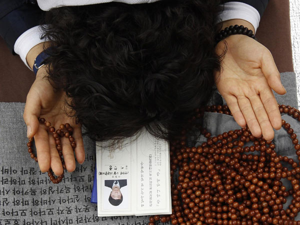 A woman prays for her son's success in the college entrance examinations as she puts a photograph of her son beside prayer beads at a Buddhist temple in Seoul Nov 9, 2011. Koreans praying for offsprings' future