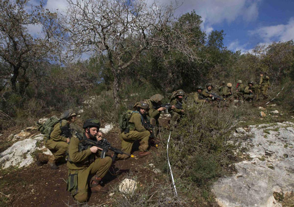 Israeli soldiers take position during an exercise in northern Israel, simulating battle conditions in Lebanon, January 18, 2012. Israeli soldiers simulate battle conditions