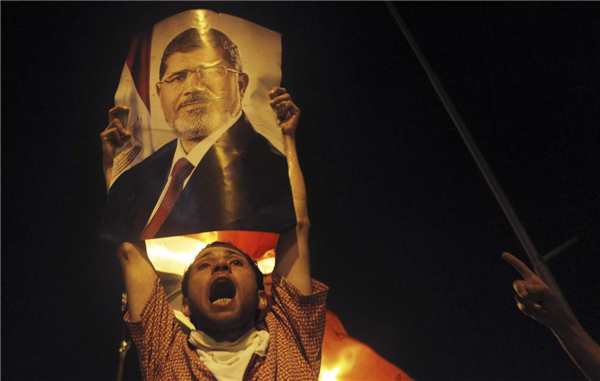 supporter of deposed Egyptian President Mohamed Mursi shouts slogans as he holds up a picture of Mursi during clashes at Ramses Square in Cairo Pro-Morsi protesters, police face off in Cairo