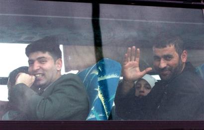 Palestinians, no names available, who were deported more than two years ago from the West Bank to Gaza wave to members of the media from a bus on the Israeli side of the Erez Crossing, in the northern Gaza Strip (news - web sites), Sunday, Feb. 20, 2005. Sixteen Palestinians and their families who were expelled by Israel to the Gaza Strip more than two years ago left Gaza en route to their homes in the West Bank on Sunday. (AP Photo/Tsafrir Abayov)