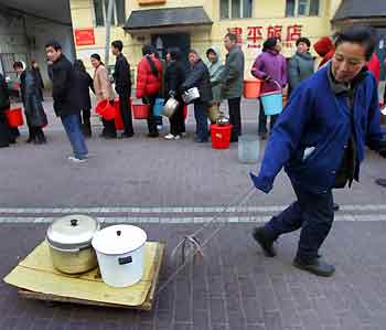 A Chinese woman pulls two pots of water on a trolley as residents line up to receive water in the city of Harbin, the capital of northeastern Heilongjiang Province, November 26, 2005. [Reuters]