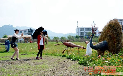 Tourists have fun with straw sculptures in Xingyi