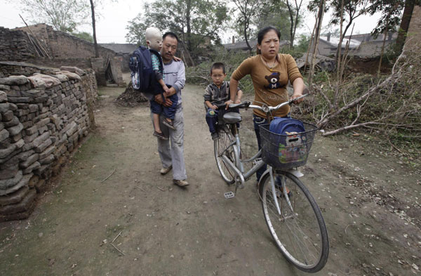 Wang Gengxiang (L), known as 'Masked Boy', and his young brother Wang Gengbao, 4, travel to their kindergarden with their parents Wang Shouwu and Yu Yanjun (R) at Mijiazhuang village on the outskirts of Fenyang, North China's Shanxi province Sept 9, 2011. Masked boy barred from kindergarten due to burns