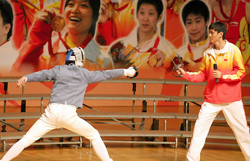 Olympic fencing champion Zhong Man gives instructions to a local resident in Hong Kong, August 30, 2008. China&apos;s Olympic gold medallists arrived in Hong Kong on Friday, kicking off their three-day visit to the city.[Xinhua]