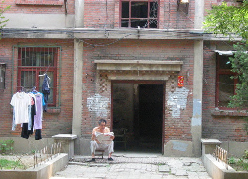 A Chinese man reads newspaper in Juixiaqiao Sub-district in Beijing, June 9, 2007. Local government in Jiuxianqiao and the real estate developer jointly organize the vote on Saturday to see if majority residents of over 5000 families accept the new compensation policy after failed attempts to reach an agreement through other ways. Both notary officials and supervisors are invited to monitor the vote that runs from 9 a.m. to 9 p.m. at six ballot booths. [Sun Yuqing/www.midnightarchive.com]
