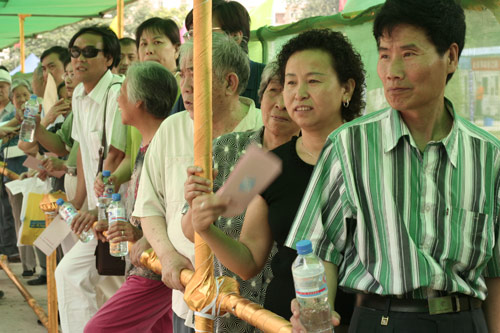 Residents wait to cast their votes on the demolishment and reconstruction of old buildings in Juixiaqiao Sub-district in Beijing, June 9, 2007. Local government and the real estate developer jointly organize the vote on Saturday to see if majority residents of over 5000 families accept the new compensation policy after failed attempts to reach an agreement through other ways. Both notary officials and supervisors are invited to monitor the vote that runs from 9 a.m. to 9 p.m. at six ballot booths. [Sun Yuqing/www.midnightarchive.com]