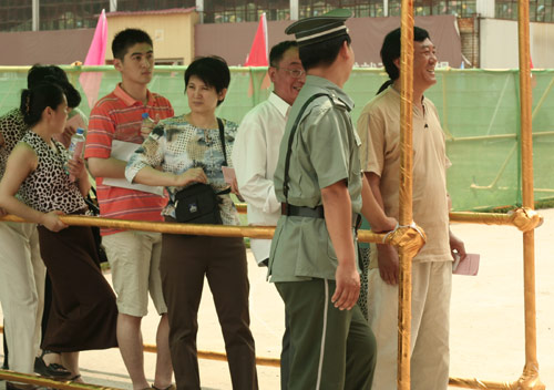 A security man talks with residents at the venue for a vote on demolishment and reconstruction of old buildings in Juixiaqiao Sub-district in Beijing, June 9, 2007. Local government and the real estate developer jointly organize the vote on Saturday to see if majority residents of over 5000 families accept the new compensation policy after failed attempts to reach an agreement through other ways. Both notary officials and supervisors are invited to monitor the vote that runs from 9 a.m. to 9 p.m. at six ballot booths. [Sun Yuqing/www.midnightarchive.com]
