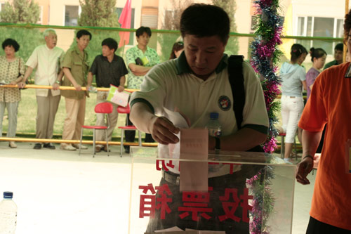 A voter casts his vote on demolishment and reconstruction of old buildings in Juixiaqiao Sub-district in Beijing, June 9, 2007. Local government and the real estate developer jointly organize the vote on Saturday to see if majority residents of over 5000 families accept the new compensation policy after failed attempts to reach an agreement through other ways. Both notary officials and supervisors are invited to monitor the vote that runs from 9 a.m. to 9 p.m. at six ballot booths. [Sun Yuqing/www.midnightarchive.com]