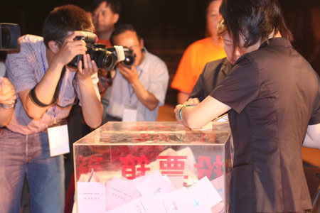 Photographers take the picture as two notary officials seal the balloting boxes after a voting on the housing demolition and compensation policy at Jiuxianqiao sub-district in Chaoyang District of Beijing, June 9, 2007. Some 3,711 families, about 57% of the 5,473 families, cast their votes on Saturday, with 2,451 votes for and 1,228 votes against the demolition and compensation plan. Thirty-two votes were invalid. [Sun Yuqing/www.midnightarchive.com]