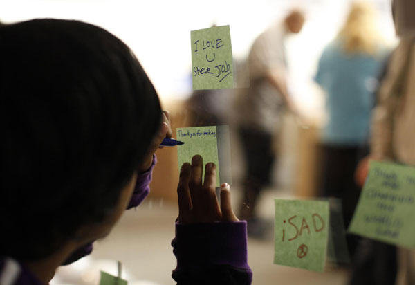 A man writes a 'thank you' note in memory of Apple co-founder Steve Jobs outside the Apple Store in San Francisco, California October 5, 2011. The world mourns Steve Jobs