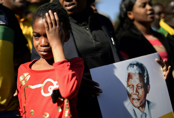 A girl weeps as she stands next to a portrait of Nelson Mandela held by ANC supporters outside the Medi-Clinic Heart Hospital, where the ailing former South African President is being treated, in Pretoria June 28, 2013. Mandela's condition 'improving' as Obama flies in